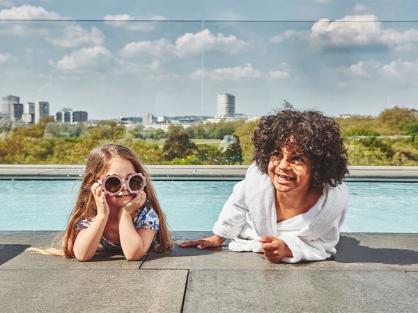 Two children, a girl and boy, by the Berkeley rooftop pool, smiling and laughing.