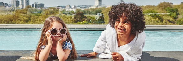 Two children, a girl and boy, by the Berkeley rooftop pool, smiling and laughing.