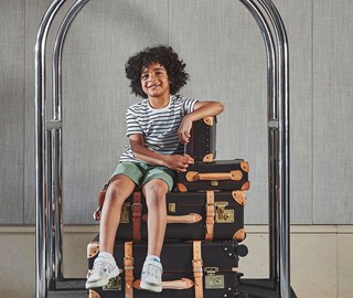 Boy sitting on suitcases on The Berkeley's luggage trolley