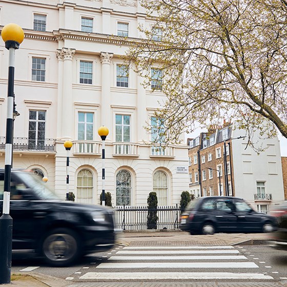 View of crossing and white residential  buildings in London, with black taxis