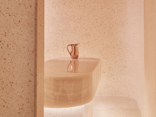 White onyx wet room at Surrenne. A copper jug sits atop the white onyx treatment table
