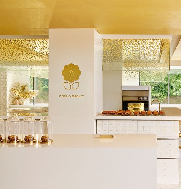 Elegant white and gold interior of Cédric Grolet's patisserie at The Berkeley, showcasing artisanal pastries under glass domes and a refined, minimalist design.