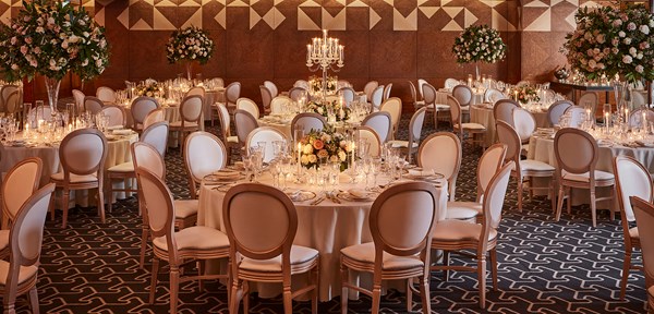 Round tables set up for a wedding, with cream coloured floral bouquets on each and candles decorating the rooms