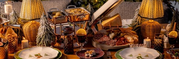 A cozy Alpine-inspired dining scene with glowing lamps, festive decor, and a gourmet spread of raclette, charcuterie, and truffle-topped dishes, creating a warm and indulgent winter feast ambiance.