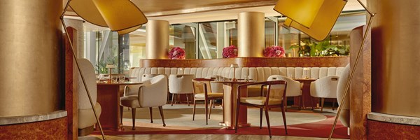 A wide-angle view of The Berkeley Café bathed in golden light, highlighting the harmonious interplay of marble, velvet textures, and fresh floral accents.